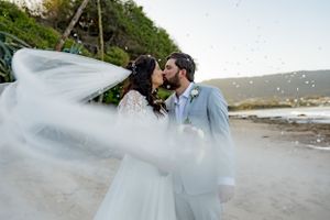 A romantic beachside wedding portrait with flowing veil in the breeze.