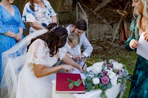Wedding ceremony participants gathered around a table signing documents with floral decorations.