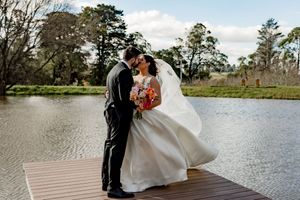 A romantic couple embraces by a serene lake with Spanish moss draped trees creating a dreamy wedding backdrop.