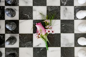 Pink flowers arranged on a black and white checkered marble surface.