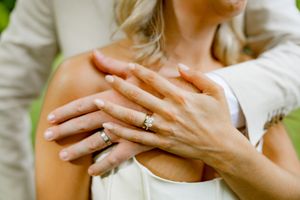 Close-up shots of hands displaying engagement and wedding rings in natural outdoor lighting.