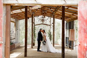 A wedding ceremony moment in a rustic wooden pavilion decorated with floral arrangements and chandeliers.