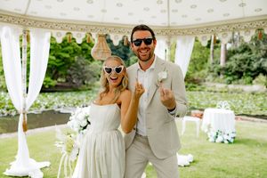 Elegant outdoor wedding reception with white decor, champagne glasses, and floral arrangements under a white tent.