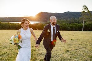 A couple in wedding attire shares romantic moments in a sunlit meadow during golden hour.