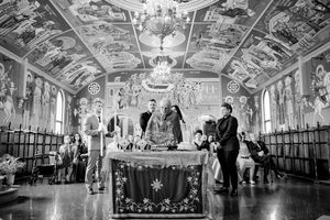 Elegant couples dancing in an ornate ballroom with baroque-style painted ceilings and crystal chandeliers.