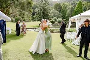 Wedding guests mingle and celebrate on a lush green lawn with white chairs and tables set up outdoors.