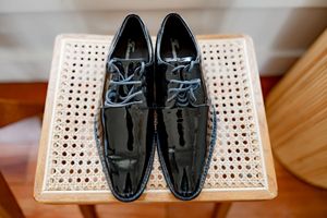 Black patent leather dress shoes displayed on a white woven surface in various angles.