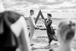 A series of black and white photos showing a couple's intimate wedding ceremony moments on a scenic beach.
