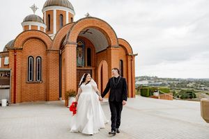 A series of wedding photos showing a couple walking along the exterior of a red brick church with arched windows and domed towers.