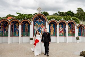 A couple walks along a path lined with colorful Orthodox church murals and arches at a monastery.
