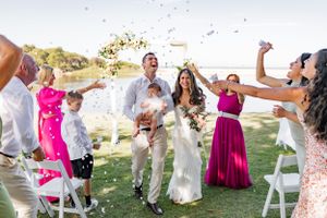 Wedding celebration with guests throwing confetti during outdoor ceremony.