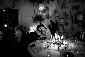 Black and white photo of bride and groom sharing an intimate moment at candlelit wedding reception table.