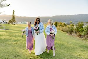 Three attendants pose in a scenic outdoor wedding setting with rolling hills in the background.