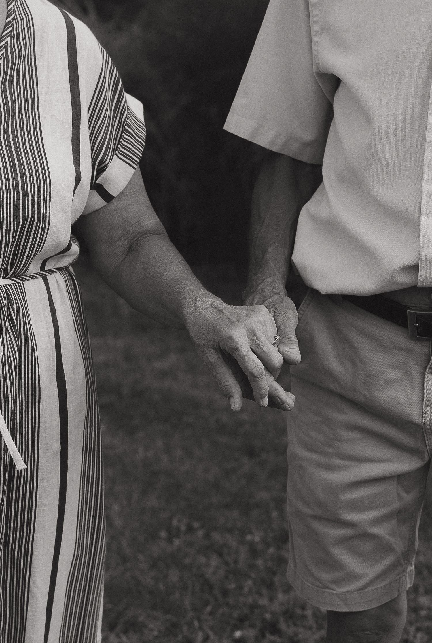Black and white close-up of hands wearing striped clothing against a dark background.