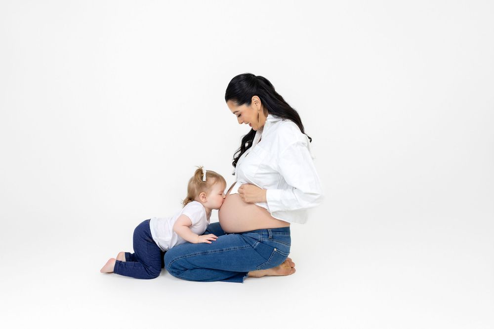 A sequence of pregnancy progress photos showing a woman laying on her side as her belly grows through the trimesters.