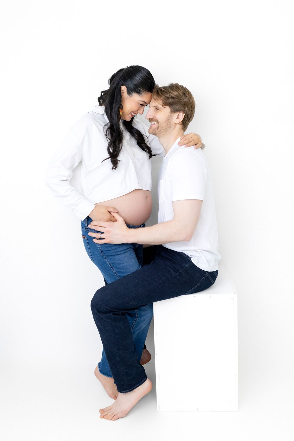 Family members embracing and sharing tender moments against white backdrop in casual attire.