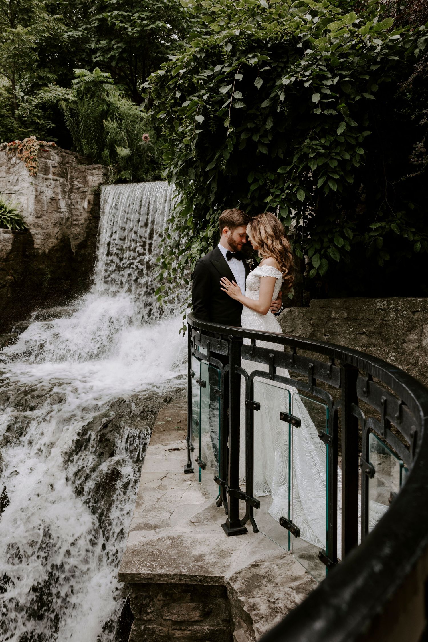 Romantic waterfall photoshoot with flowing white dress and natural scenery in the background.