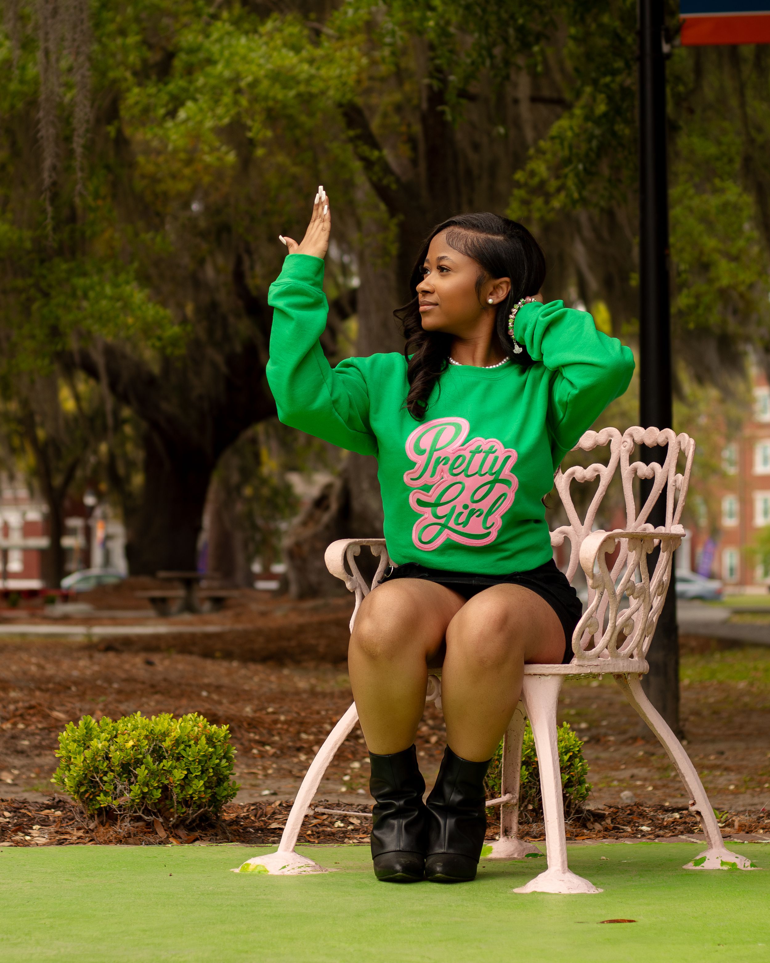 Person in bright green sweatshirt sitting on white chair outdoors.