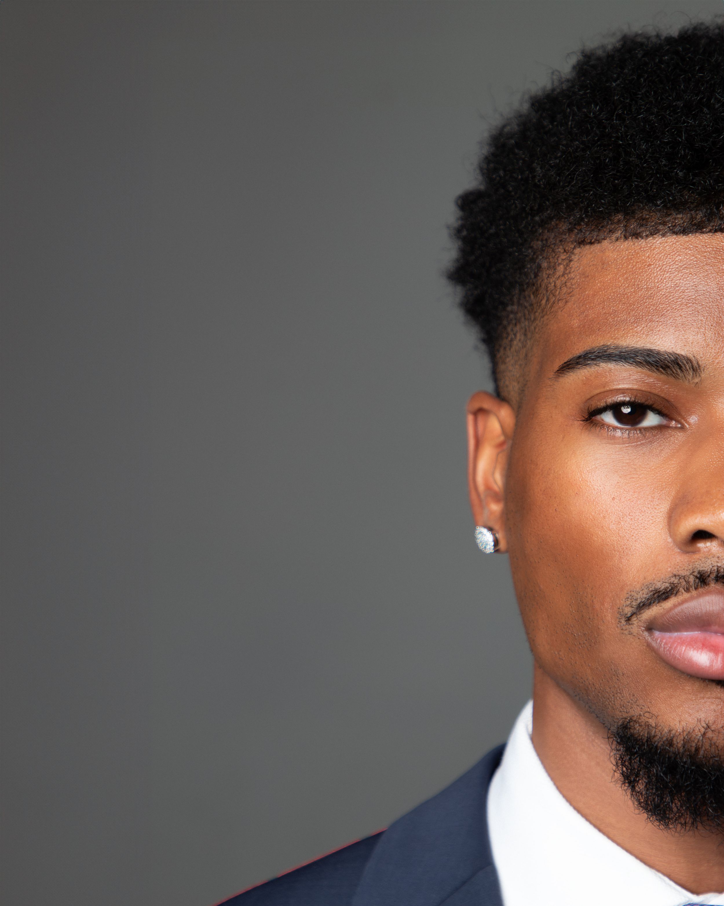 Close-up professional headshot against grey background.