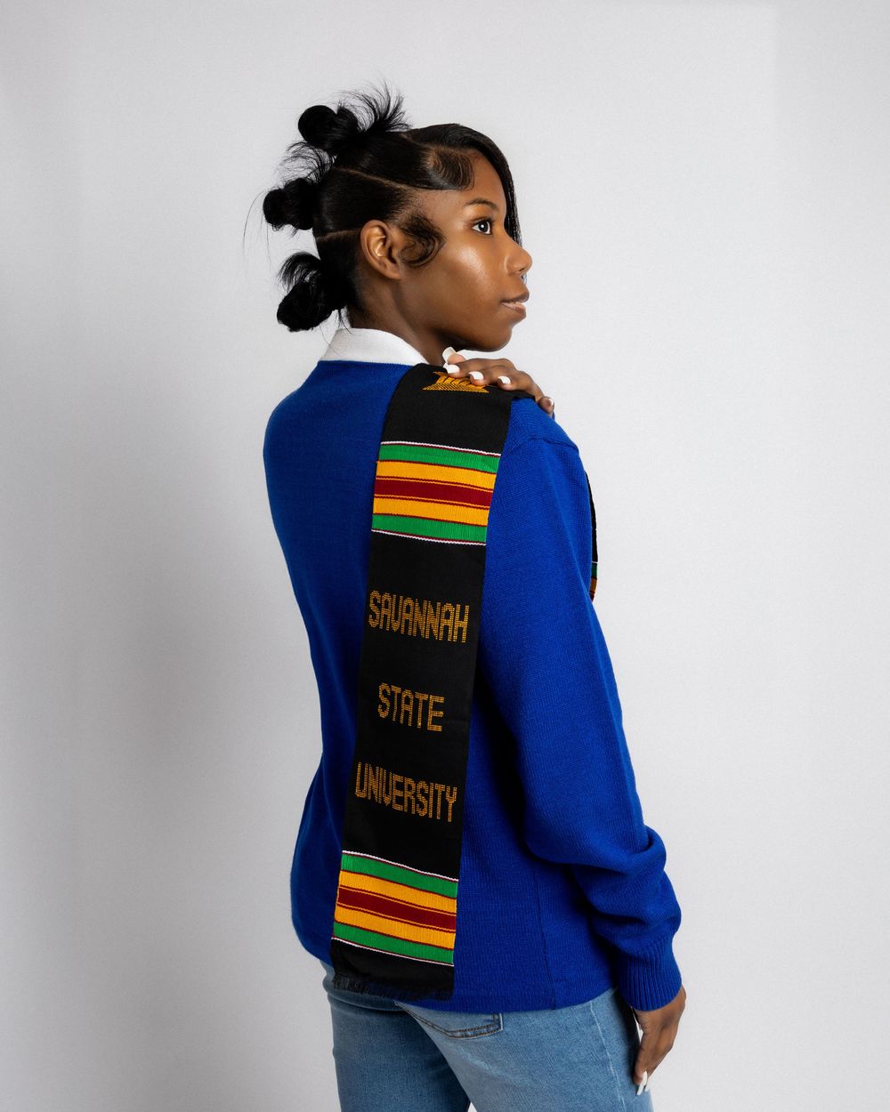 A blue college sweatshirt with green and red striped accents and university text displayed from multiple angles.