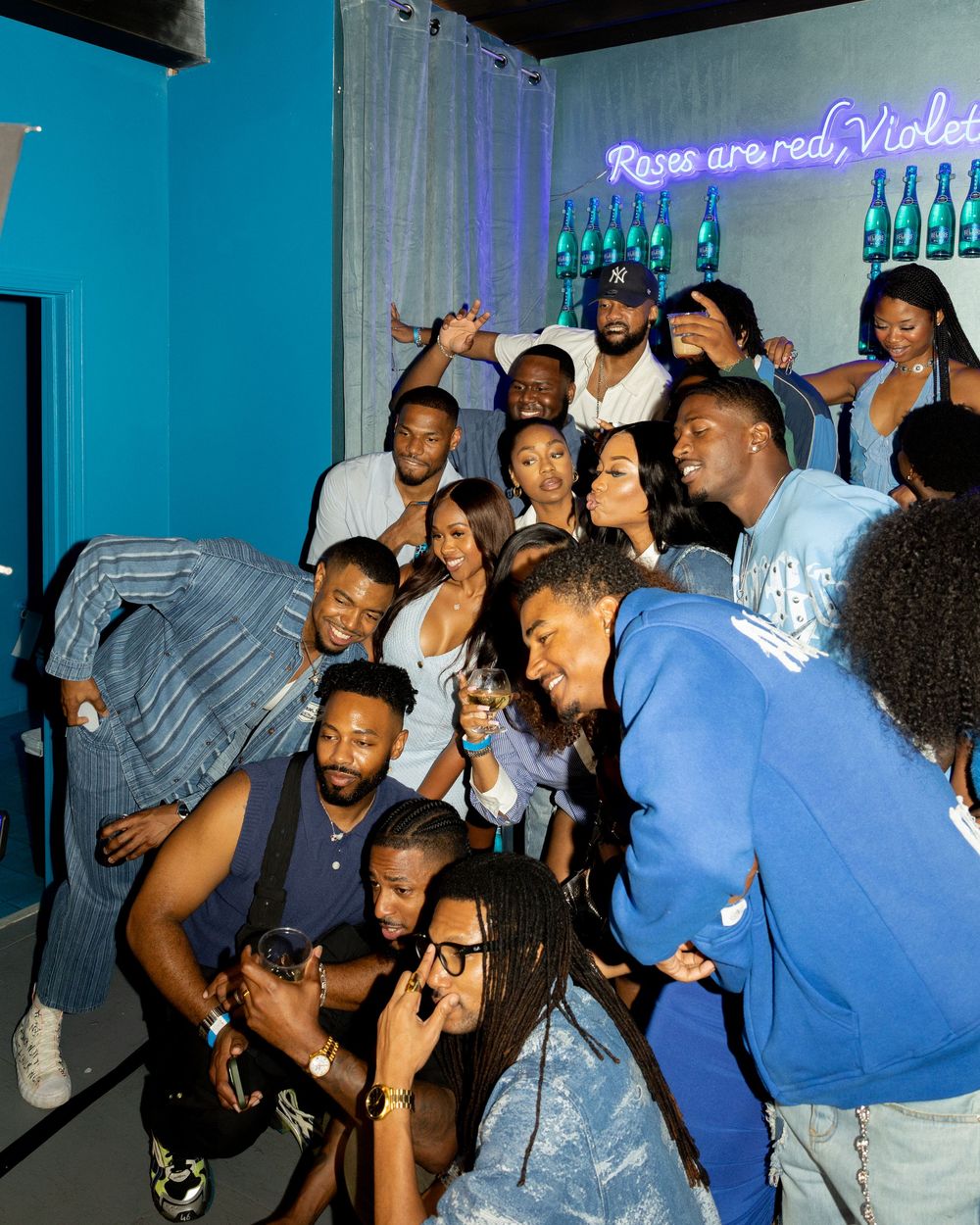 People dancing and enjoying themselves at a nightclub with blue lighting and neon signage in the background.