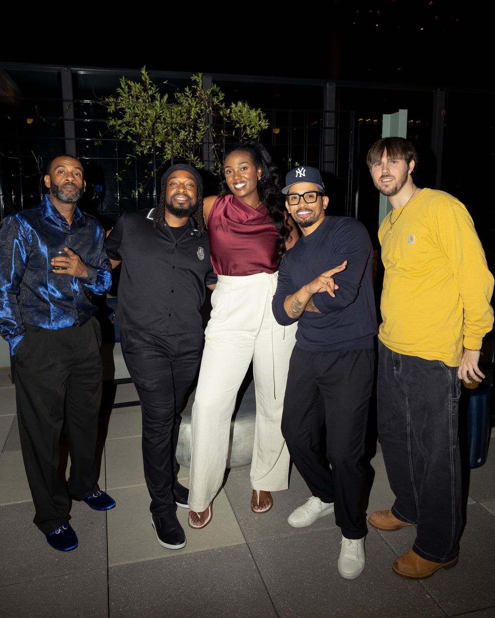 A group of people sitting together on steps at night wearing casual attire in black, white, and yellow clothing.