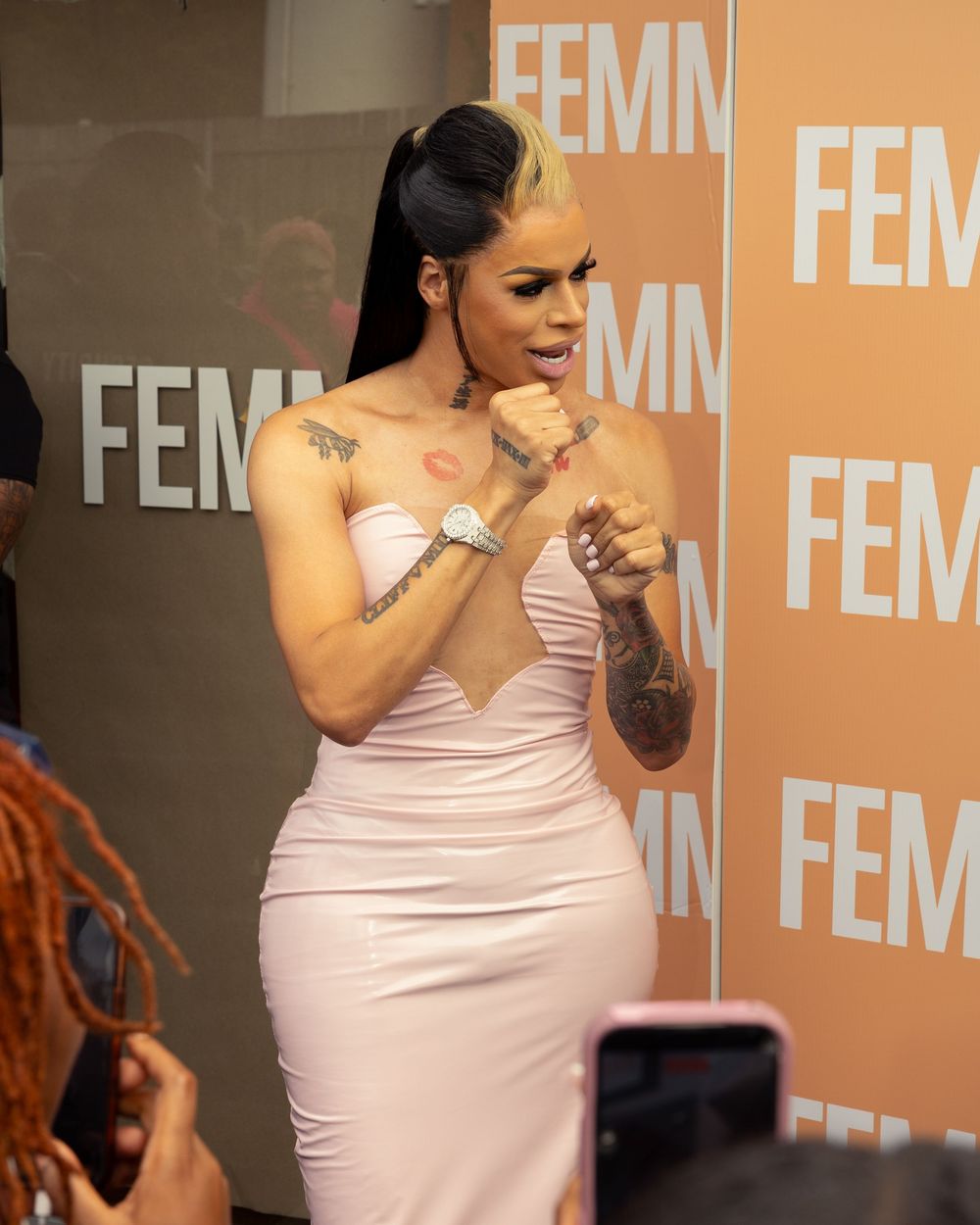 A person in a pink strapless dress performs an emotional gesture sequence on stage.