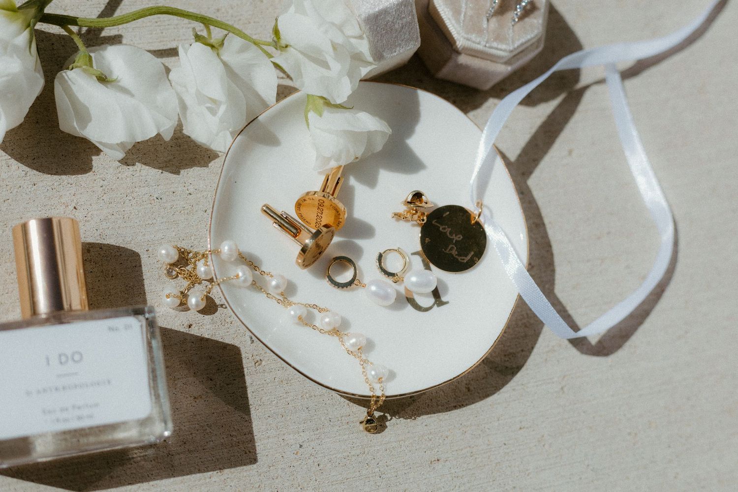 Wedding rings suspended on a pearl string with a polaroid photo on white fabric.
