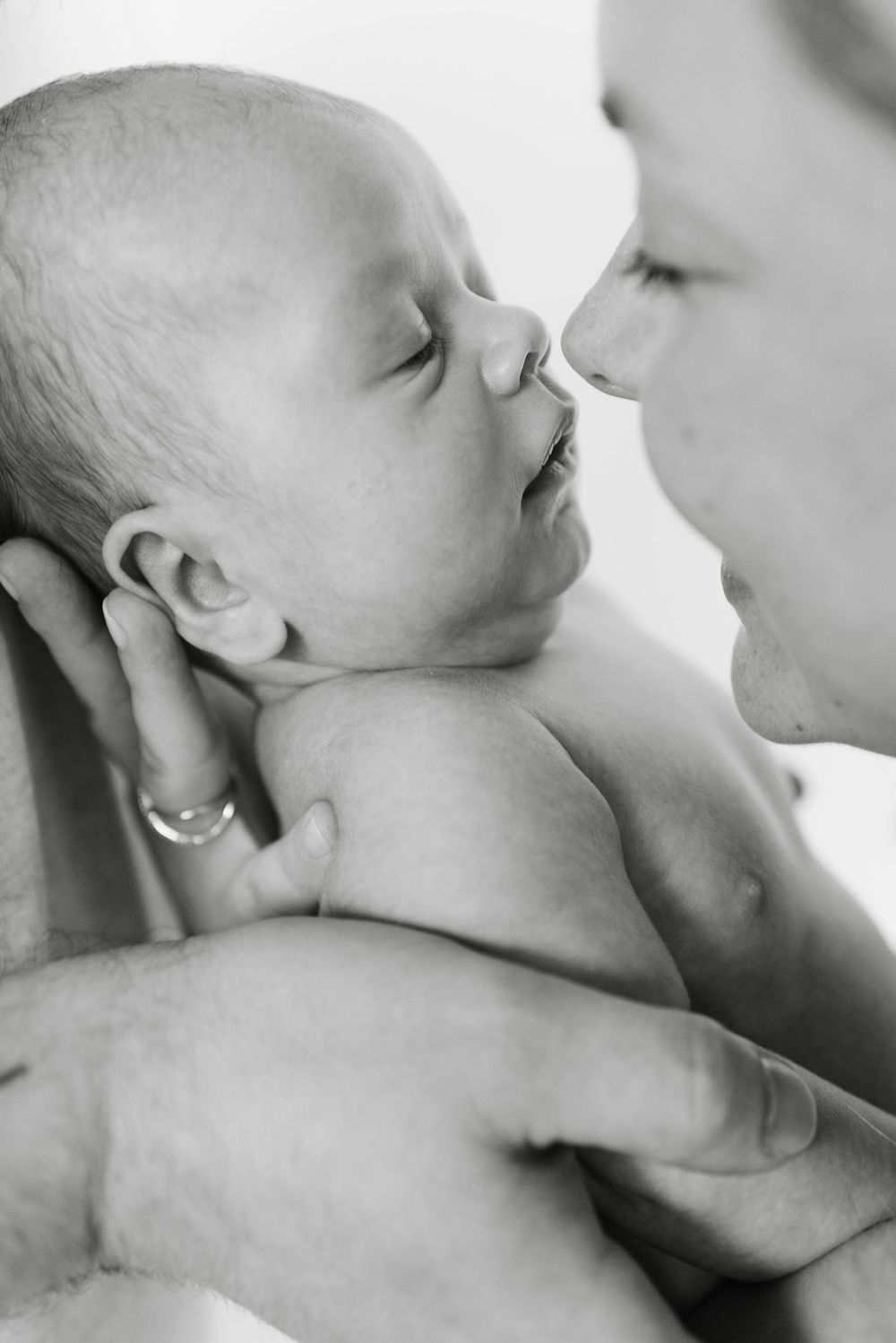 Close-up of mom kissing newborn baby during intimate family photo session in Toronto - heartfelt and tender family photography