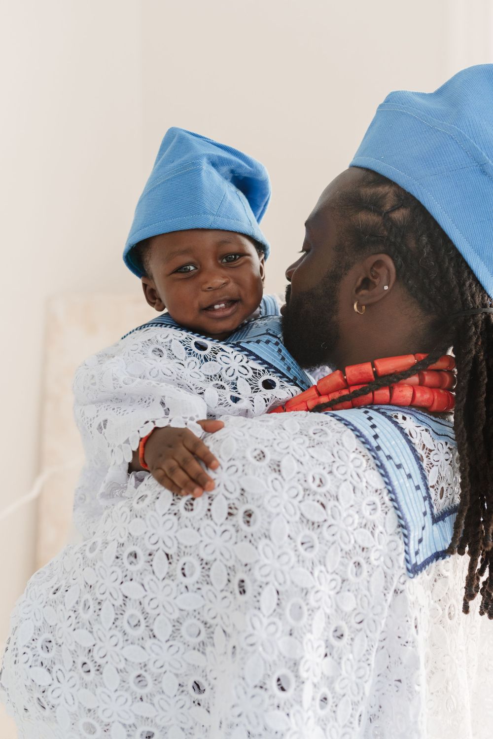 Baby smile while in dad's lap in traditional Nigerian clothing at mint room, captured by Toronto Family Photographer Jess GC Photography
