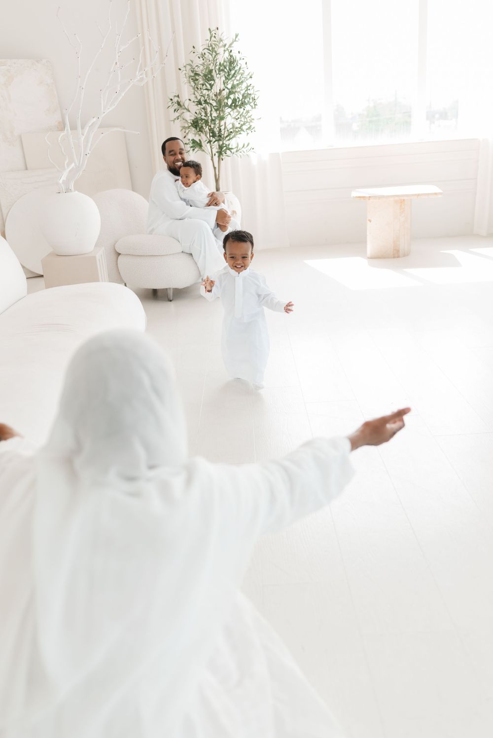 Twins family photography captured at mint room studios, twin boy running to hug and embrace his mom for a Toronto Family Photography session