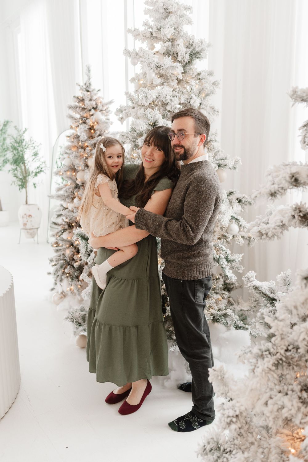 Toronto family posing in a bright room around christmas decorations for family photoshoot in Mint Room Studios, captured by Jess GC.