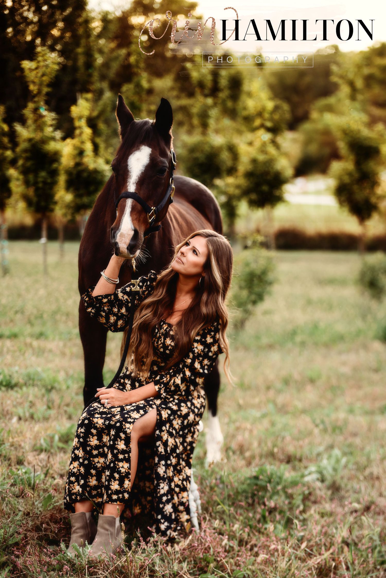 A floral dress-clad figure poses with a beautiful black horse in a sunlit meadow.