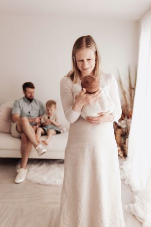 A series of minimalist family lifestyle photos showing tender moments in a bright white room with neutral decor.