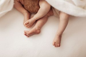 Tiny baby feet and toes on soft white bedding create a tender newborn photography composition.