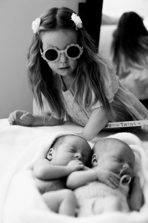 A mother wearing sunglasses and a flower accessory tenderly holds and nurses her newborn baby in a series of intimate portraits.