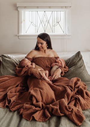 A series of photos showing a parent and baby snuggling together on a green couch wrapped in a brown blanket.