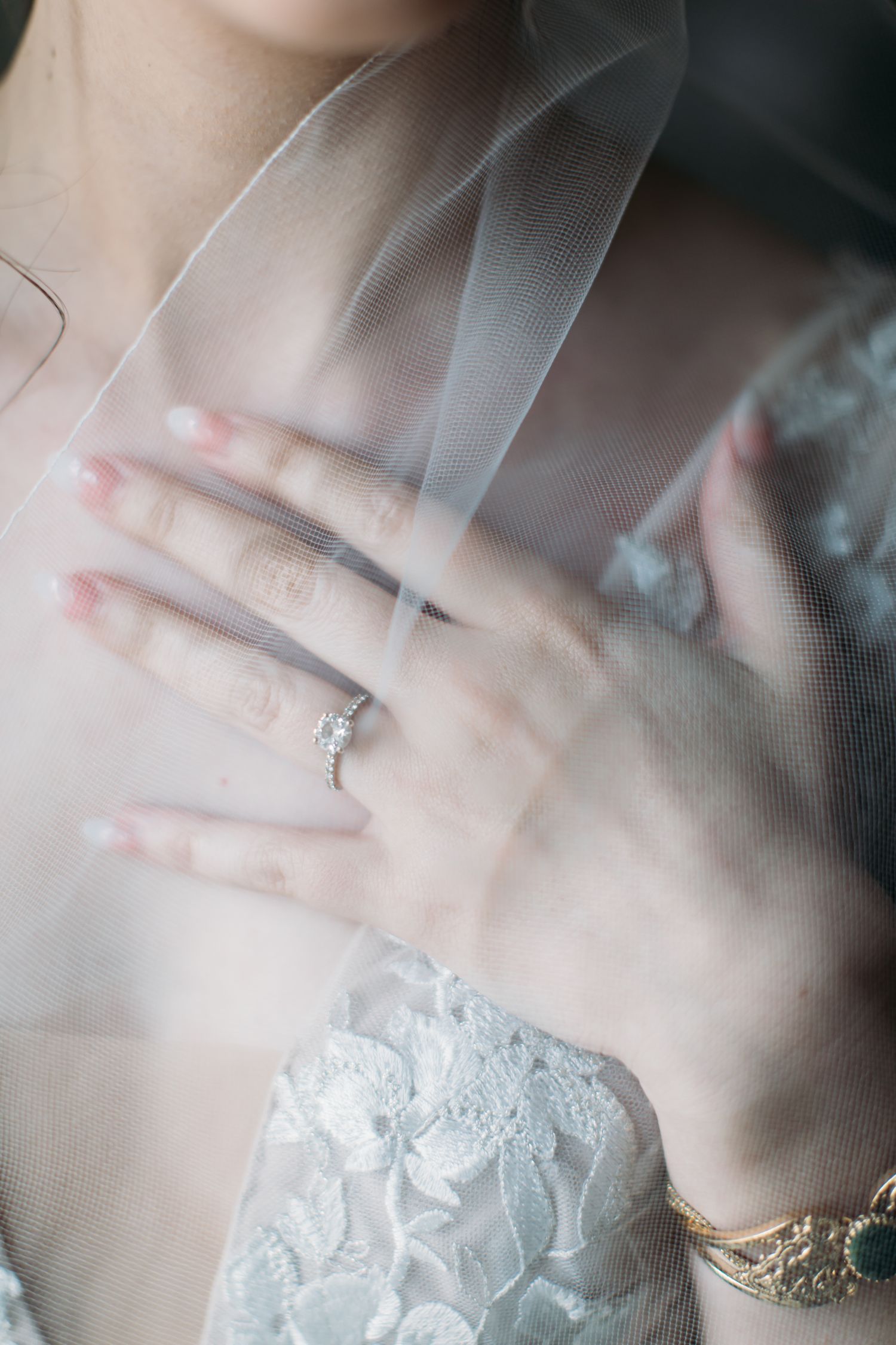 Close-up of elegant engagement ring through delicate bridal veil.
