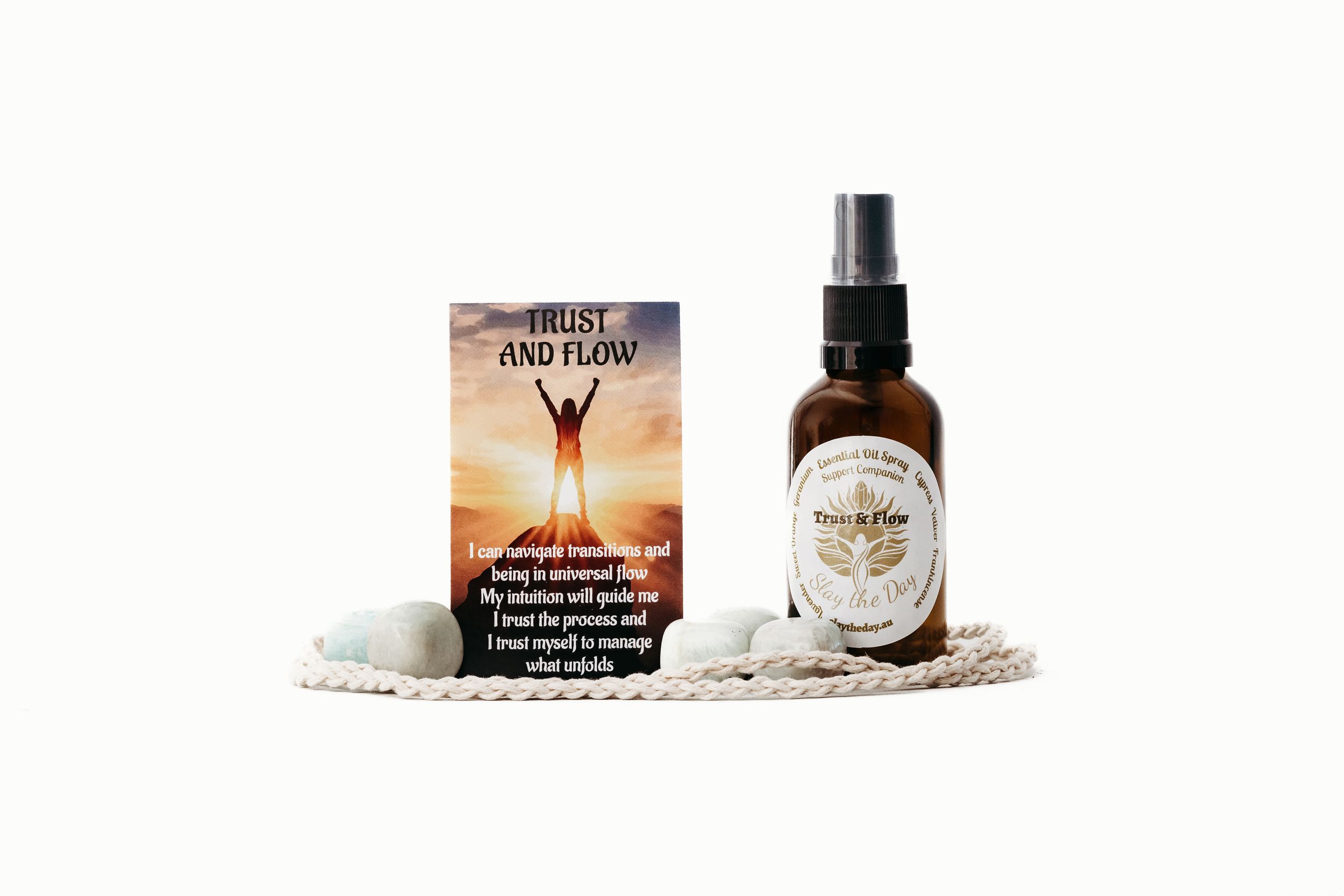 Trust and Flow aromatherapy spray bottle with affirmation card and decorative stones on a braided rope mat.