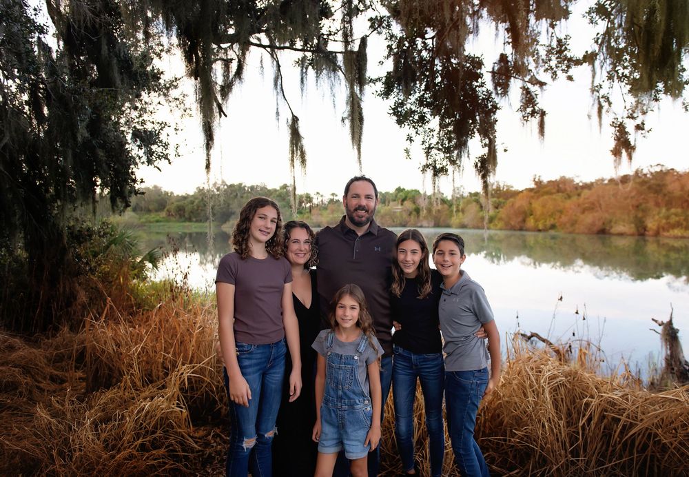 Scenic landscape with Spanish moss hanging from trees near water at sunset.
