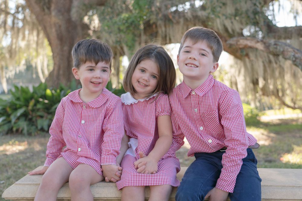 Children in coordinating red and white outfits share laughs during an outdoor photo session.