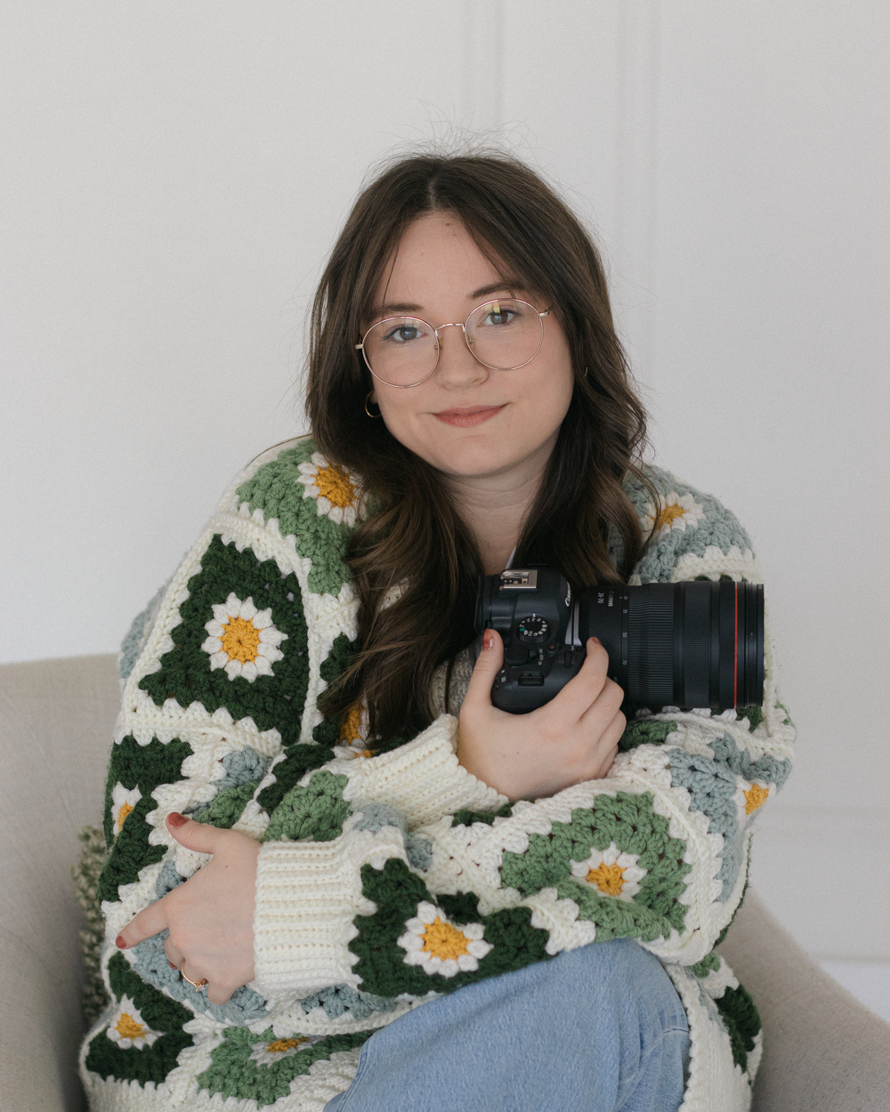 Photographer in casual attire smiling while reviewing images on digital camera.