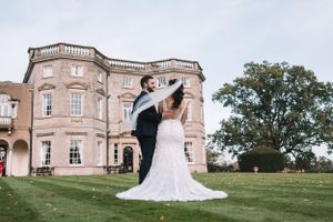 A romantic wedding couple shares an elegant dance pose on the lawn of a grand historic mansion estate at Bourton Hall, Nottingham.