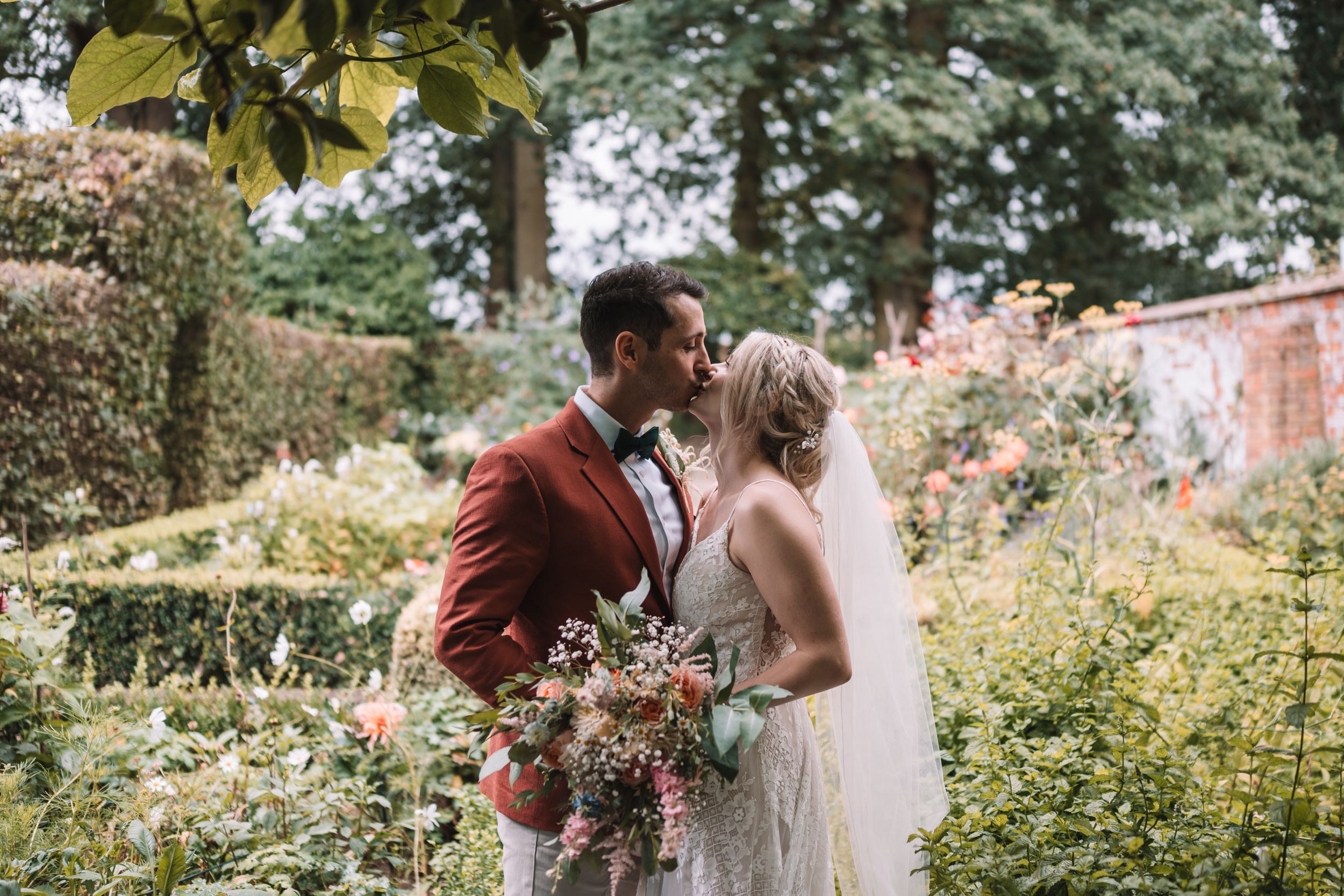 A couple shares a romantic kiss in a lush garden setting at Park Farm in Daventry, Northamptonshire.