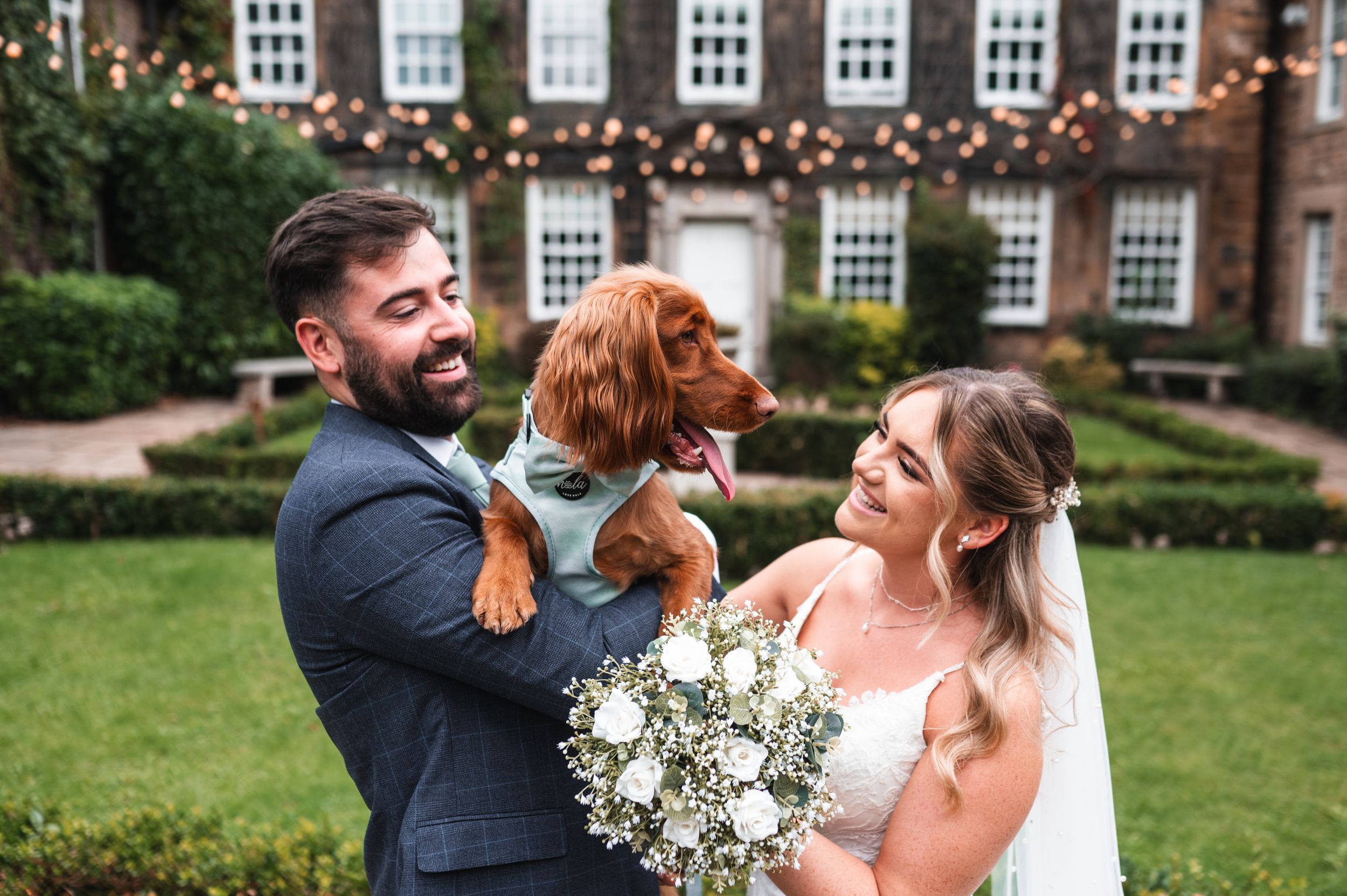 A couple and their adorable red spaniel celebrating at an outdoor wedding at Whitley Hall, South Yorkshire.