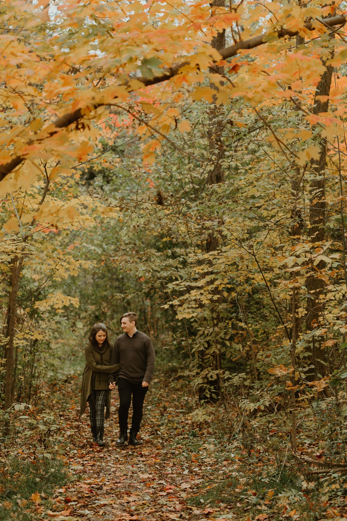Romantic couple walking in the woods under a canopy of leaves.