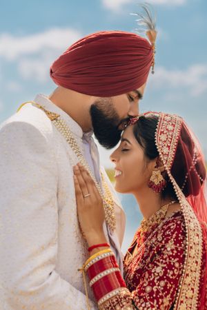 A tender moment between newlyweds in traditional Sikh wedding attire.