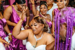 Wedding celebration with energetic dancing and bridesmaids in purple dresses.