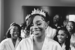 Black and white candid of bride laughing with bridesmaids during wedding preparations.