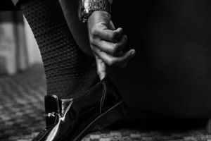 Close-up of hands adjusting formal footwear in black and white.